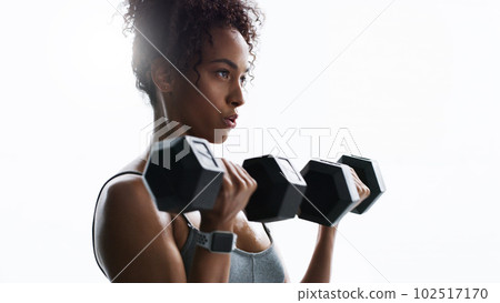 Show yourself how strong you are. a young woman working out with dumbbells in a gym. 102517170