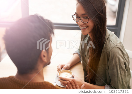 This coffee is as warm as our love. a young couple sitting in a coffee shop on a date. This coffee is as warm as our love. a young couple sitting in a coffee shop on a date. 102517251