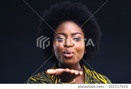 Sending some love your way. a young woman blowing a kiss against a dark background. 102517420