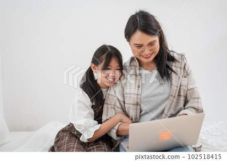 Asian family mother and daughter use the laptop together happiness moment Asian family mother and daughter use the laptop together happiness moment 102518415