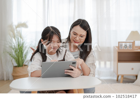 Asian family mother and daughter using the tablet in the home Asian family mother and daughter using the tablet in the home 102518417