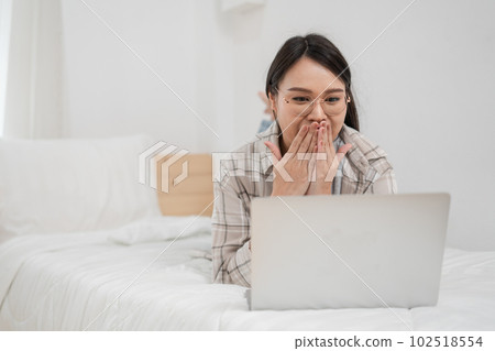 Young Asian woman lying on her bed using laptop video call in bedroom. Young Asian woman lying on her bed using laptop video call in bedroom. 102518554