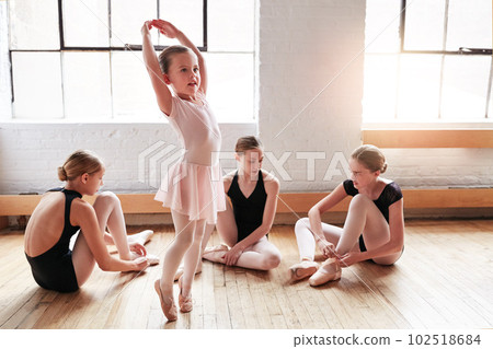 She could do ballet before she could walk. an adorable little girl learning ballet with a group of older girls in a dance studio. 102518684
