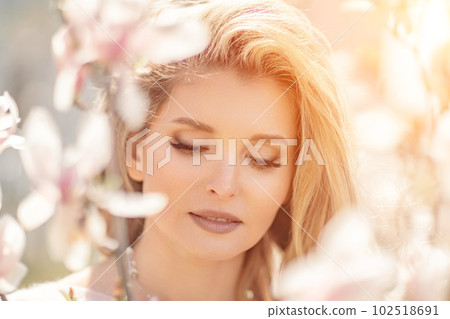 Magnolia woman portrait. Happy middle aged woman enjoying the smell in a blooming spring garden. Beautiful magnolia bushes, large flowers. Magnolia woman portrait. Happy middle aged woman enjoying the smell in a blooming spring garden. Beautiful magnolia bushes, large flowers. 102518691
