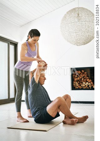 Building strength and flexibility through yoga. an instructor guiding a senior man in a yoga class. 102518834