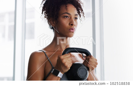 It starts with a strong mindset. a young woman working out with kettlebells in a gym. It starts with a strong mindset. a young woman working out with kettlebells in a gym. 102518838