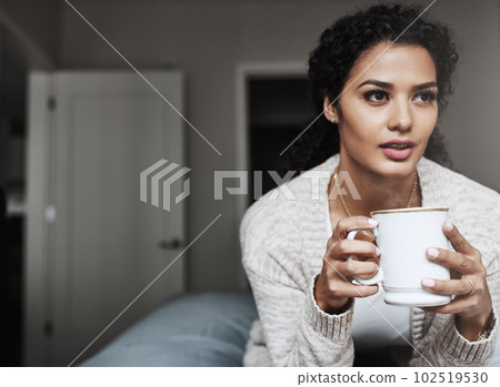 Nothing like the great indoors. a cheerful young woman drinking coffee while being seated on a couch inside at home during the day. 102519530