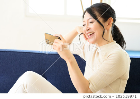 中間的女人坐著看著智能手機 102519971