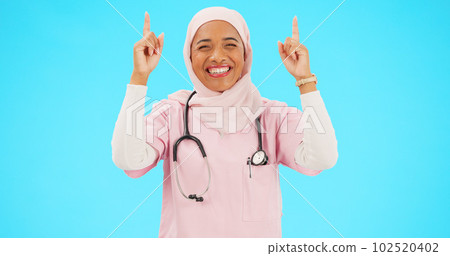 Muslim nurse, happy woman and pointing finger portrait with space for healthcare, religion or happiness. Islamic female medical worker with hand, smile and hijab for announcement on blue background 102520402