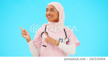 Woman doctor pointing to mockup isolated on blue background for healthcare presentation or product placement space. Happy face of nurse or medical muslim person show advertising mock up in studio 102520404