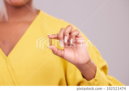 Pharmaceutical, hand and woman with a pill in a studio for healthcare, wellness or recovery medication. Medical, medicine and closeup of female person with tablet capsule isolated by gray background. 102521474