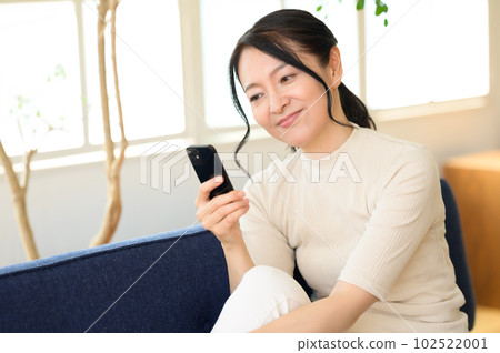 A middle-aged woman thinking about a smartphone A middle-aged woman thinking about a smartphone 102522001