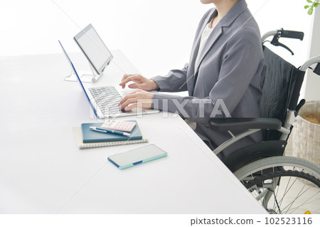 Business woman in a wheelchair using a laptop in the office Faceless 102523116