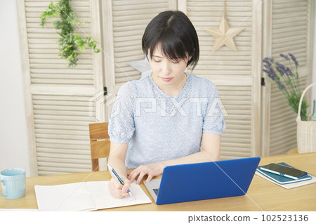 Woman studying with a laptop in the living room Woman studying with a laptop in the living room 102523136