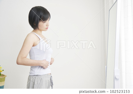 A woman who cares about her belly fat in front of the mirror 102523153