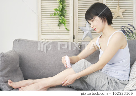 Woman doing self hair removal on her legs at home 102523169