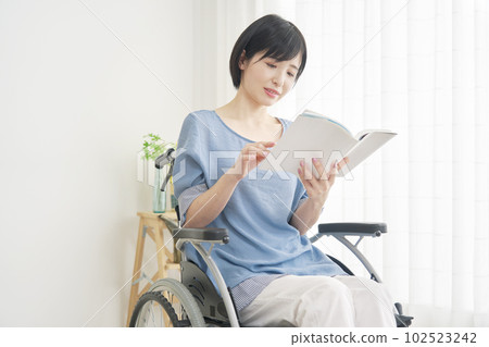 A woman in a wheelchair reading in the living room 102523242