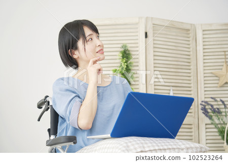 一位坐在輪椅上的女士在客廳裡使用筆記本電腦進行想像 102523264