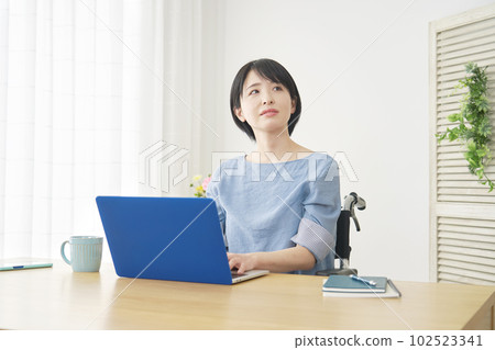坐在輪椅上的女人在客廳裡使用筆記本電腦 坐在輪椅上的女人在客廳裡使用筆記本電腦 102523341
