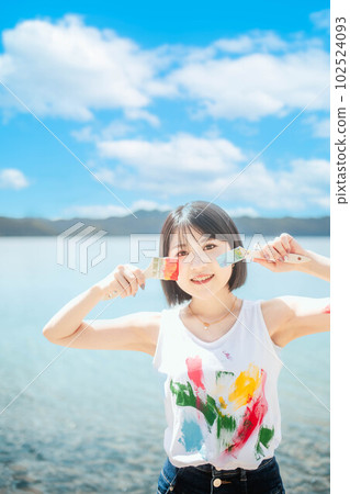 美麗的女人在藍天下用五顏六色的顏料作畫 102524093