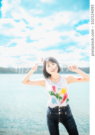 美麗的女人在藍天下用五顏六色的顏料作畫 102524095