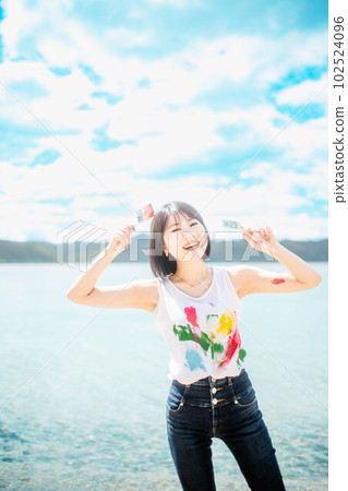 美麗的女人在藍天下用五顏六色的顏料作畫 102524096