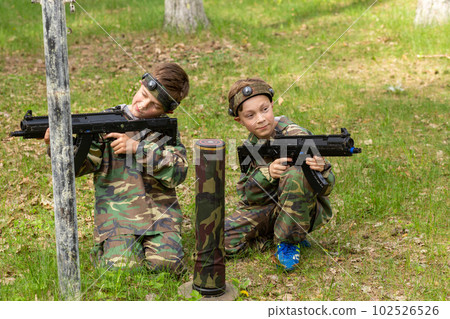 Two boys weared in camouflage playing laser tag in special forest playground. 102526526