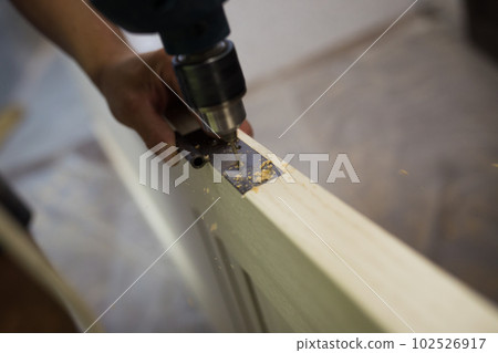 Drilling a hole in the furniture to install a lock on the door close-up. Drilling a hole in the furniture to install a lock on the door close-up. 102526917