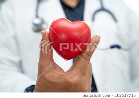 Doctor holding a red heart in hospital ward, healthy strong medical concept. Doctor holding a red heart in hospital ward, healthy strong medical concept. 102527716