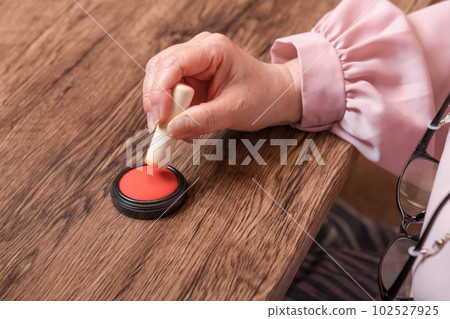 [Woman putting ink on seal] 102527925