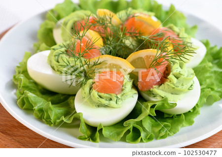 Stuffed eggs with avocado and salmon 102530477