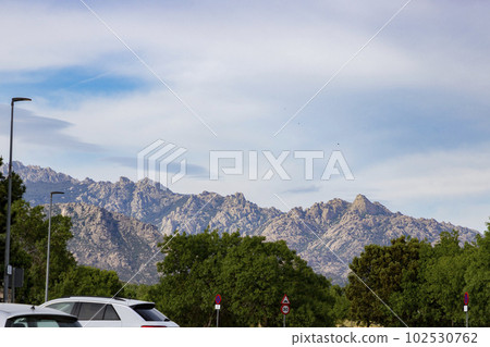 Mountains. Views of some rocky mountains with a field full of green trees and land with a cloudy sky. Horizontal photography. 102530762