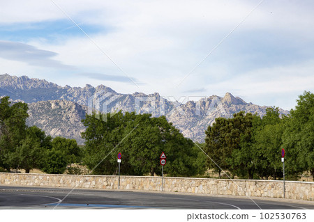 Mountains. Views of some rocky mountains with a field full of green trees and land with a cloudy sky. Horizontal photography. 102530763
