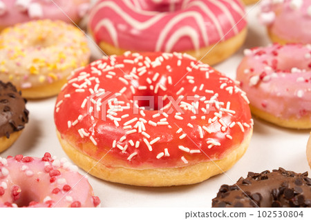 Donuts with red and pink glaze, top view. Lots of donuts, sweet and delicious food Donuts with red and pink glaze, top view. Lots of donuts, sweet and delicious food 102530804