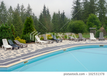 Outdoor swimming pool mountain hotel pool resort chair pool lounge chair relax mountains forest resort. Sunbed mountain resort chaise longue. Blue water forest hotel poolside chairs. Nobody, no people Outdoor swimming pool mountain hotel pool resort chair pool lounge chair relax mountains forest resort. Sunbed mountain resort chaise longue. Blue water forest hotel poolside chairs. Nobody, no people 102531378