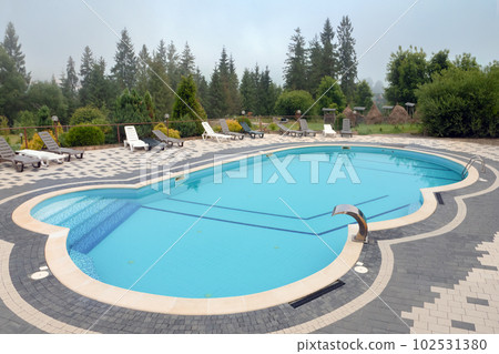 Outdoor swimming pool mountain hotel pool resort chair pool lounge chair relax mountains forest resort. Sunbed mountain resort chaise longue. Blue water forest hotel poolside chairs. Nobody, no people 102531380