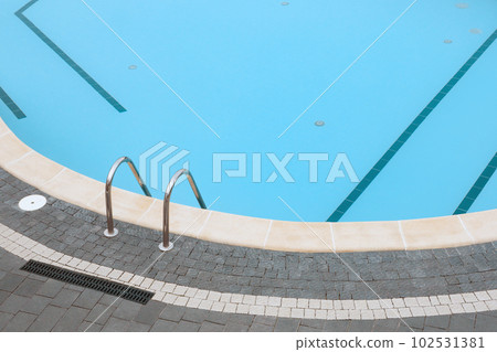 Swimming pool stone pavement tiles stone paving poolside background blue water surface. Ladder pool border. Edge pool stair 102531381