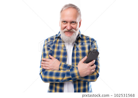 handsome 50s mid aged gray-haired man with a beard in a shirt with a smartphone on a white handsome 50s mid aged gray-haired man with a beard in a shirt with a smartphone on a white 102531568