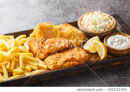 Tasty Fish Fry with coleslaw, French fries, tartar sauce and lemon closeup on the wooden board. Horizontal Tasty Fish Fry with coleslaw, French fries, tartar sauce and lemon closeup on the wooden board. Horizontal 102531591