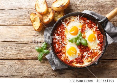 Eggs in Purgatory is a delicious Southern Italian dish consisting of fried eggs in a spicy tomato sauce with onions and garlic closeup on the skillet. Horizontal top view 102531595
