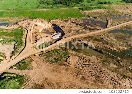 Picturesque landscape of a sand pit with a road and ponds shot from the air Picturesque landscape of a sand pit with a road and ponds shot from the air 102532715