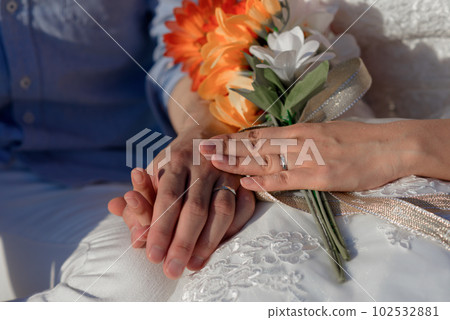 Man and woman, newlyweds holding hands with blurred background. 102532881