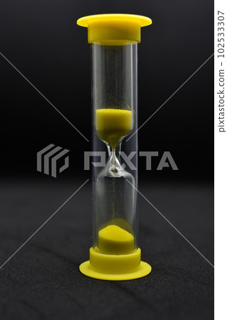 Glass hourglass on a black background. Multicolored glass hourglass. Glass hourglass on a black background. Multicolored glass hourglass. 102533307