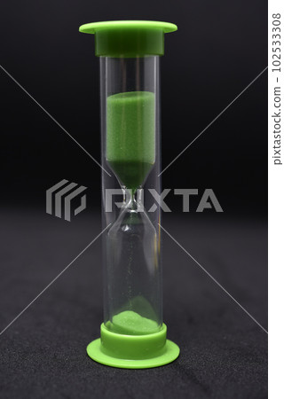 Glass hourglass on a black background. Multicolored glass hourglass. Glass hourglass on a black background. Multicolored glass hourglass. 102533308