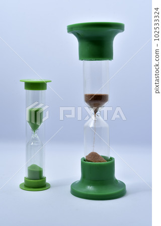 Glass hourglass on a white background. Multicolored glass hourglass. 102533324