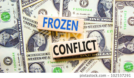 Frozen conflict symbol. Concept words Frozen conflict on beautiful wooden block. Beautiful background from dollar bills. Business and Frozen conflict concept. Copy space. 102537291