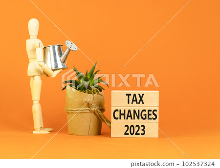 Tax changes 2023 symbol. Concept words Tax changes 2023 on wooden blocks on a beautiful orange table orange background. Businessman icon. Business Tax changes 2023 concept. Copy space. 102537324