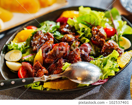 a plate of hot salad with caramelized meat. a plate of hot salad with caramelized meat. 102537401