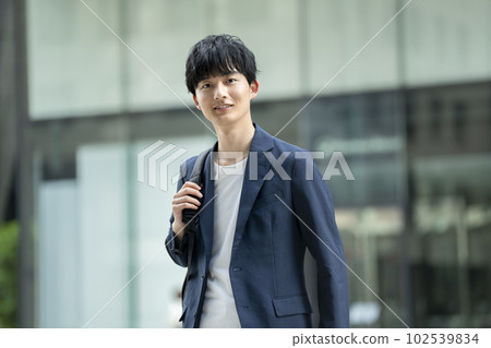 A man in his twenties looking at the camera with a backpack A man in his twenties looking at the camera with a backpack 102539834