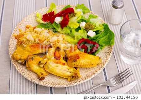 Appetizing chicken wings with rice and a vegetable salad 102544150